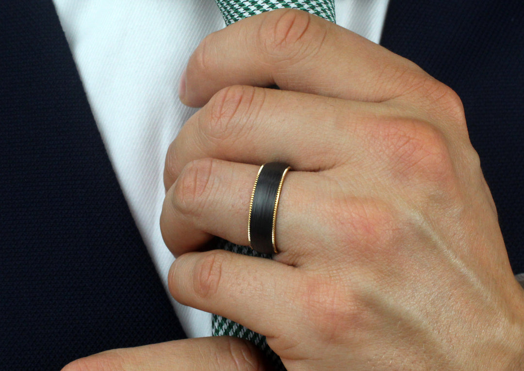 Model wearing Pair of 6.5mm wide 18ct yellow gold & Black Carbon Fibre ring; traditional court shaped profile with milgrain edging detail.